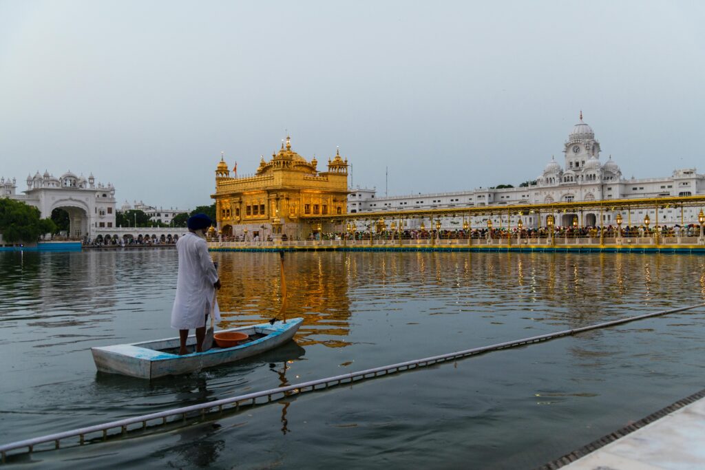 A serene view of the Golden Temple in Amritsar at twilight with a man on a boat.