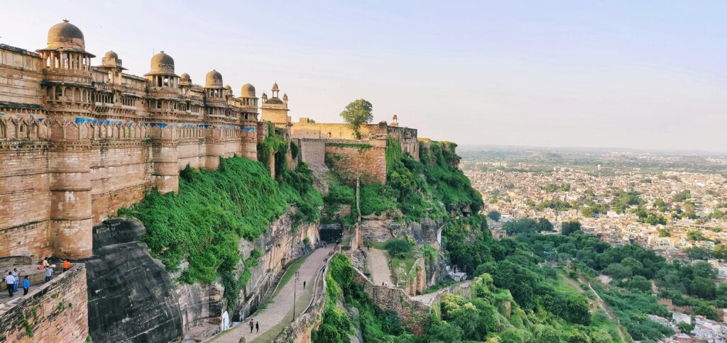 Majestic view of Gwalior Fort in India, showcasing historic architecture and lush landscape.