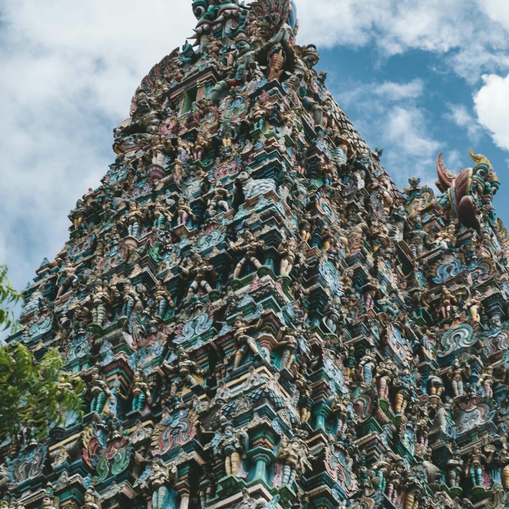 Intricate carvings on a traditional Hindu temple tower under a bright blue sky.